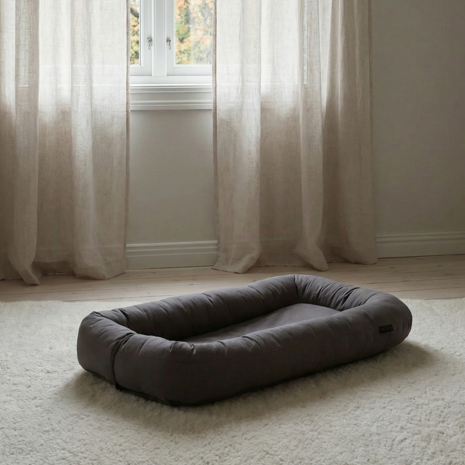 En mørkegrå rektangulær kjæledyrseng med hevede polstrede sider.