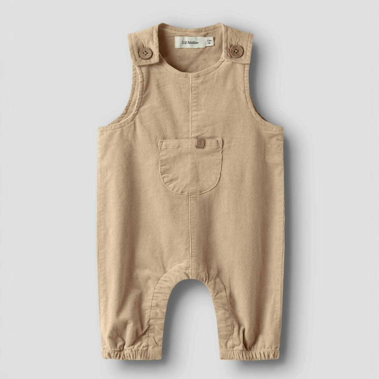 Frontvisning av en baby lysbrun cordfløyel-overall med skulderknapper, brystlomme og elastiske ankler.