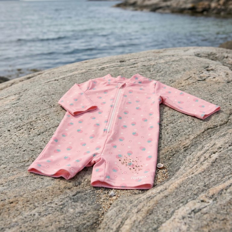 Rosa langermet babysvømmedrakt med frontglidelås og mønster av jordbær og lyseblå former.