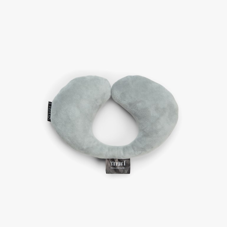 Lys grå U-formet nakkepute i mykt stoff, vist ovenfra på hvit bakgrunn.