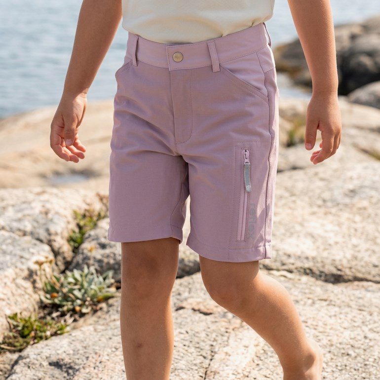 Barnets lilla shorts med knappelukking og en glidelåslomme på benet, kombinert med en lys beige topp.